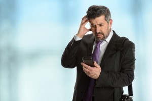 Worried Hispanic businessman looking at cellphone